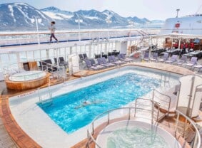 Guest jogging on the pool deck while another guest is swimming in pool, Silver Cloud, Monacobreen, Svalbard