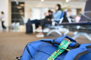 Lanyard of sunflowers, symbol of people with invisible or hidden disabilities, tied on a travel bag on the floor of an airport.