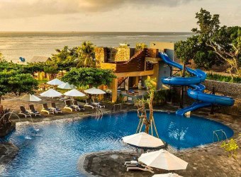 Beachfront view of Grand Mirage Resort & Thalasso Spa in Bali with palm trees and ocean backdrop