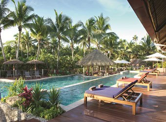 Oceanfront view of Outrigger Fiji Beach Resort with palm trees and traditional Fijian architecture