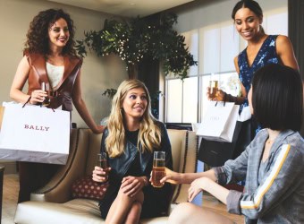 Four ladies sitting in a cafe with shopping bags from a shopping outlet