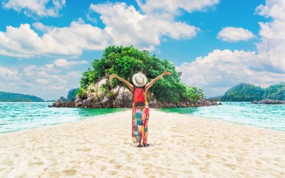Lady standing on sand with a tropical island in front of her
